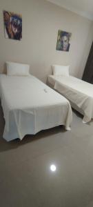 two beds in a room with white sheets and posters at Hermosa casa amoblada in Barranquilla +7 photos