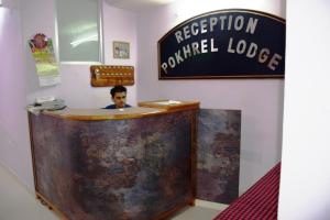 a man sitting at a reception desk in a room at Pokhrel Lodge in Kalimpong