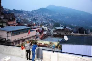 two people standing on top of a building looking at a city at Pokhrel Lodge in Kalimpong