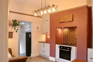a kitchen with an orange wall with a stove at Hyem at Cullercoats in Cullercoats +43 photos