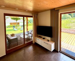 a living room with a television and a patio at Lux Chalet - Sauna and Hot Tub in Topolšica