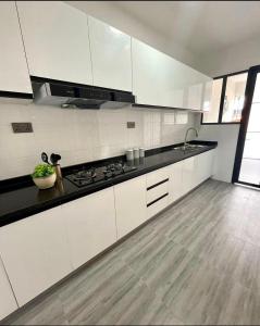 a kitchen with white cabinets and a black counter top at Staroot residency in Nairobi