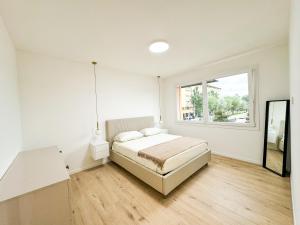 a white bedroom with a bed and a window at Sacali's House Mare in Porto Santa Margherita di Caorle