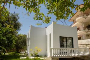 a white house with a porch and trees at Olivium Rooms in Vlorë