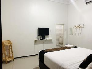 una camera da letto con un letto e una TV a schermo piatto di Tjahaja Baroe Syariah Mitra RedDoorz At Dukuh Kupang a Surabaya