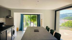 a kitchen with a table with chairs and a large window at 3 pièces avec piscine privative in Collioure +14 photos