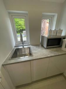 eine Küche mit Spüle und Mikrowelle in der Unterkunft Thimble Cottage in Buckinghamshire