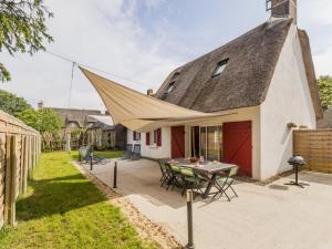 une maison avec un toit triangulaire avec une table dans l'établissement Chaumière au calme avec terrasse, à 9 km des plages, 3 chambres, parking privé et équipements bébé. - FR-1-306-1276, à Saint-Lyphard