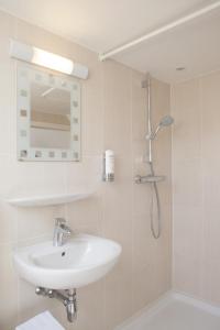 a white bathroom with a sink and a shower at Hof Ten Hullenhove in Ostend