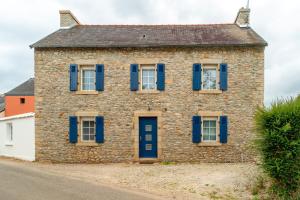 an old stone house with blue shutters on a street at Ma Kalon - Maison pour 8 avec parking in Plomodiern