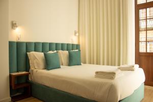 a bedroom with a large bed with a green headboard at ORM- Flores Apartment in Porto