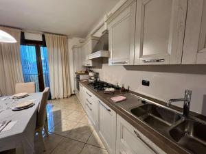 a kitchen with white cabinets and a sink and a table at Il Rifugio del Viaggiatore in Bagnolo