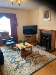 a living room with a fireplace and a television at The Cottage at Hillhead Farm in St. Andrews