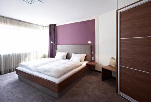 ein Schlafzimmer mit einem großen Bett und einer lila Wand in der Unterkunft Hotel Am Helmwartsturm in Andernach
