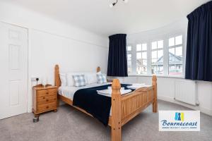 a bedroom with a wooden bed with blue curtains at Bournecoast Family chalet bungalow - garden -9600 in Mudeford