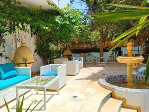 a patio with a fountain and chairs and a table at Hôtel Romane in Hammamet