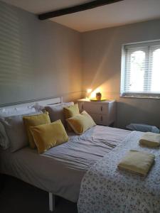 a bedroom with a bed with yellow pillows and a window at Heath Cottage Lower Southrepps north Norfolk in Cromer