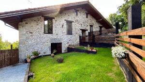 a stone house with a green yard in front of it at Apartamentos Iparagirre in Ispáster