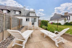a patio with white chairs and a house at À 350m du bord de mer, maison pour 4 in Saint-Pierre-Quiberon