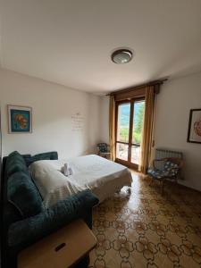 a bedroom with a bed and a couch and a window at Casa Rossa al Lago - Apt Terrazza in Spinone Al Lago