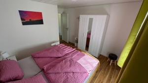 a bedroom with a bed with a pink comforter at Weiherblick in Scheidegg