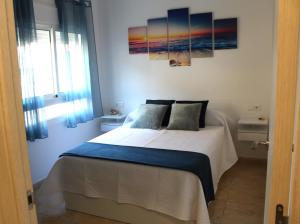 a bedroom with a bed with two paintings on the wall at Apartamento Encanto Marino in Sant Carles de la Ràpita