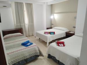 a hotel room with two beds with towels on them at Hotel Nuevo Ara in C&aacute;ceres
