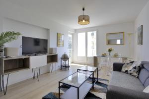 a living room with a couch and a tv at Appartement des Chênes - Welkeys in Anglet