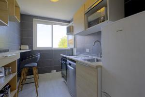 a small kitchen with a sink and a window at Appartement des Chênes - Welkeys in Anglet