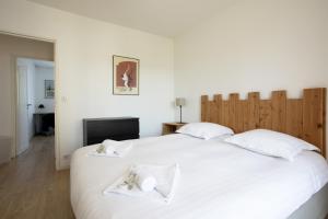 a bedroom with a large white bed with two towels at Appartement des Chênes - Welkeys in Anglet +4 photos