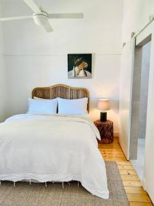 a bedroom with a white bed with a wooden headboard at Thunder St Cottage Light Bright Home in Bendigo