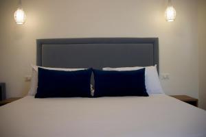 a bedroom with a bed with blue pillows and two lights at Galaxy Rooms Tropea in Drapia