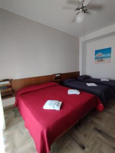 a bedroom with two beds with red sheets and a fan at Hotel Luca in Rimini
