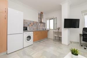 eine Küche mit einer Waschmaschine und einem TV in der Unterkunft Verano en Chiclana in Chiclana de la Frontera