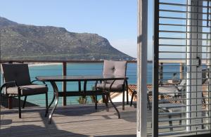 een tafel en stoelen op een balkon met uitzicht op de oceaan bij Apartment The Nook in Fish hoek