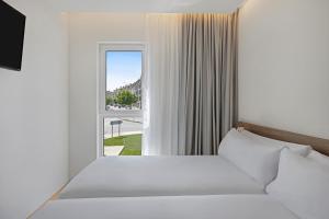 米拉多罗B&B HOTEL Santiago Milladoiro的带床和窗户的卧室