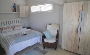 a bedroom with a bed and a chair and a window at Apartment The Nook in Fish hoek