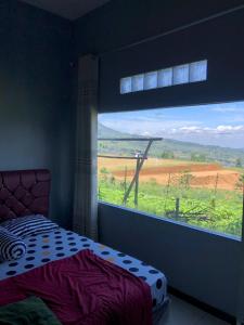 a bedroom with a window with a view of a field at RR Homestay seroja in Garung