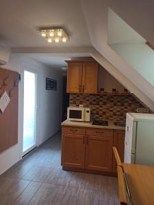 a kitchen with wooden cabinets and a white microwave at Orchidea II in Hévíz