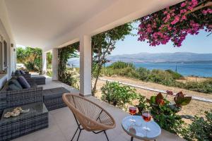 a patio with two chairs and a table with two glasses of wine at Villa Aionia in Lepeda in Lixouri +20 photos