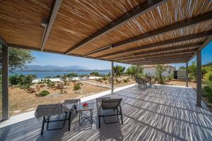 a wooden deck with chairs and a table under a wooden pergola at Villa Aionia in Lepeda in Lixouri