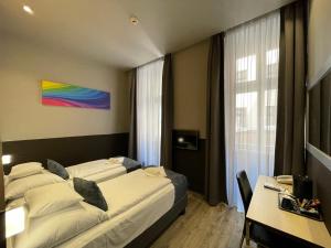 a hotel room with two beds and a desk and a window at Carat Boutique Hotel in Budapest