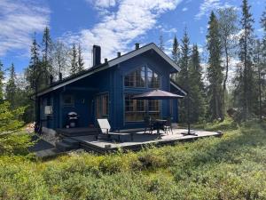 una casa azul con una mesa y una silla en una cubierta en Saiho, en Syöte