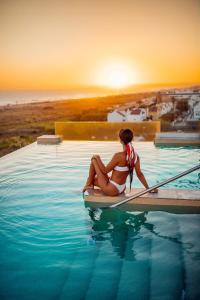 サアラ・デ・ロス・アトゥネスにあるZahara Beach & Spa by QHotels - Adults Recommendedの水中のパドルボードに腰掛けたビキニ姿の女性