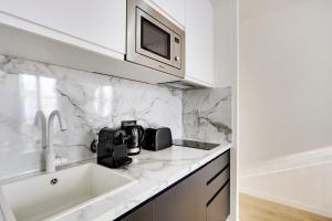a white kitchen with a sink and a microwave at Luxury in the heart of Paris - 1BR-4P - Bourse in Paris +7 photos