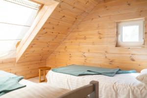 a room with two beds in a wooden wall at 2bedroom house in Mērsrags