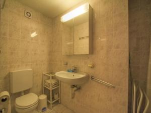 a bathroom with a sink and a toilet and a mirror at Apartment Les Rocailles by Interhome in Anzère