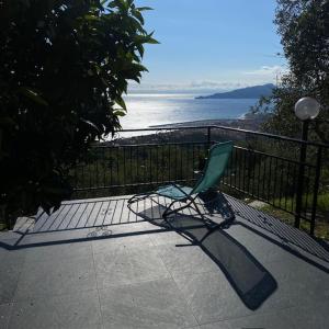 a green chair sitting on a balcony overlooking the ocean at Terrazza Oneto in Crocetta