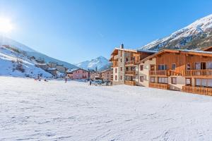 un lodge de ski dans la neige avec des montagnes en arrière-plan dans l'établissement Résidence Les Balcons de Val Cenis Village, à Lanslevillard