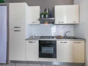 a white kitchen with white cabinets and a stove at Apartment Maestrale by Interhome in Marina di Cecina +30 photos